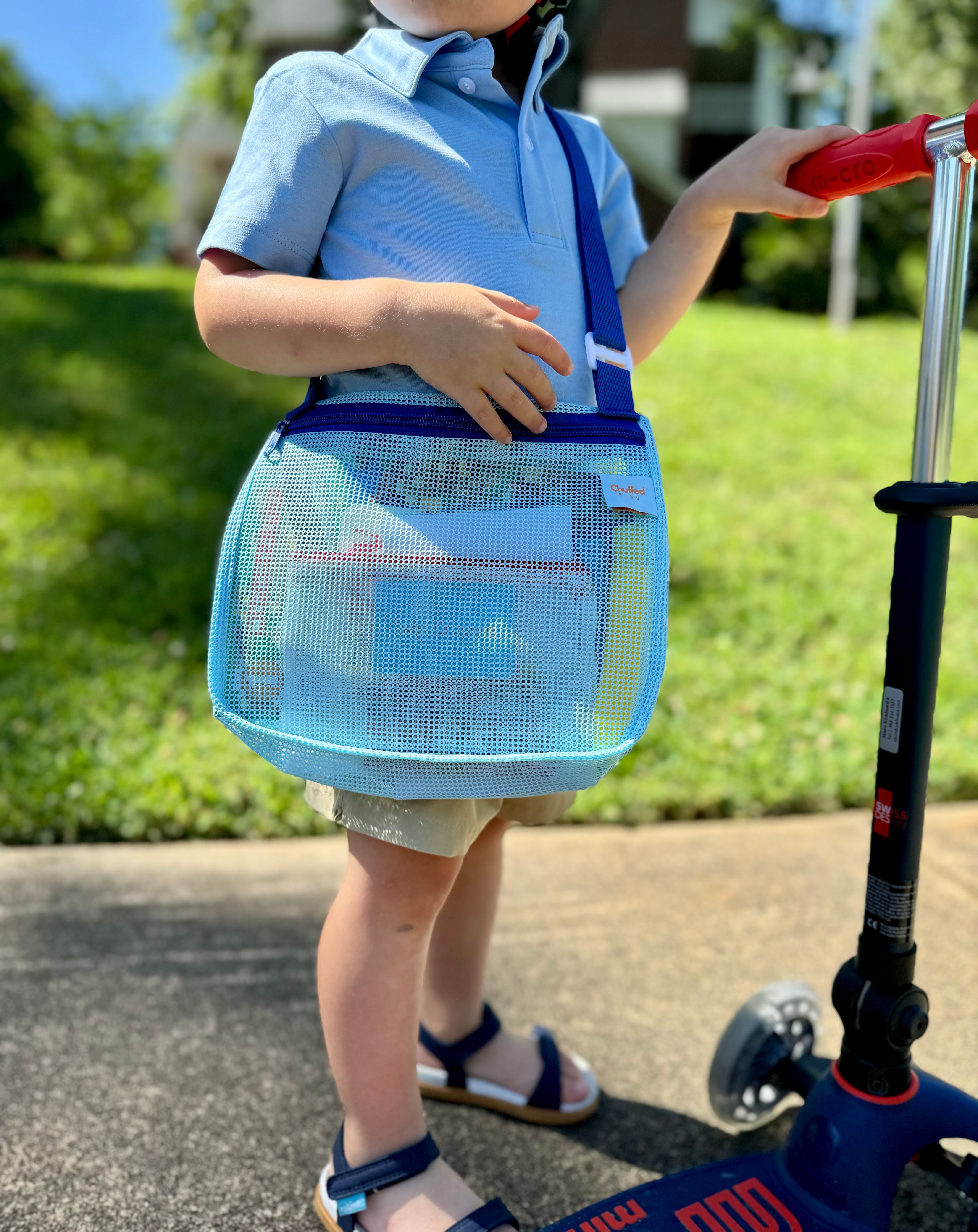 toddler with blue play bag and scooter